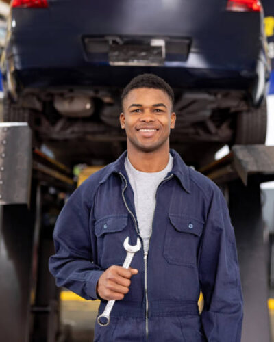 Portrait of a happy African American mechanic working at an auto repair shop and looking at the camera smiling